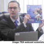 Photo of Education Commissioner Mike Morath holding up TEA 2023 Annual Report during State Board of Education Meeting