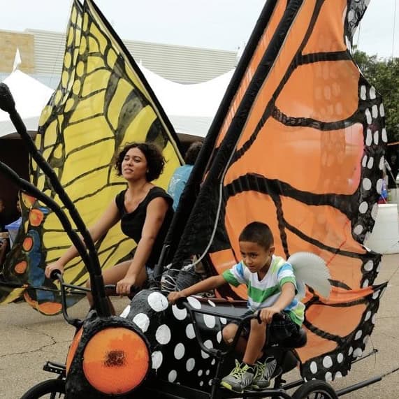 Photo: The bike zoo, child and adult riding on bicycles with large butterfly wings attached