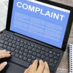 Image: hands typing on laptop computer with Complaint image