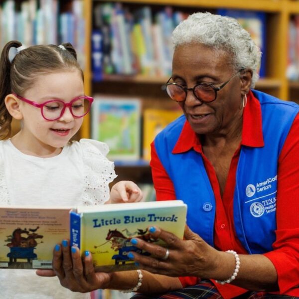 Photo: elementary age girl being read to by "foster grandparent"